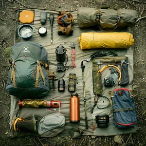 Collection of camping and hiking gear arranged on a mat outdoors.